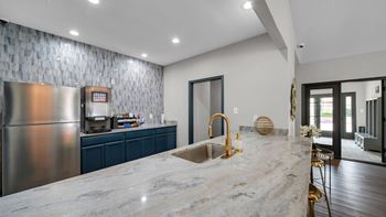 A modern kitchen with a marble countertop and stainless steel appliances.